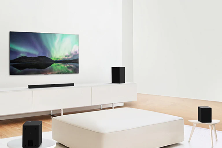 Televisore e soundbar in un soggiorno bianco con al centro un divano bianco.