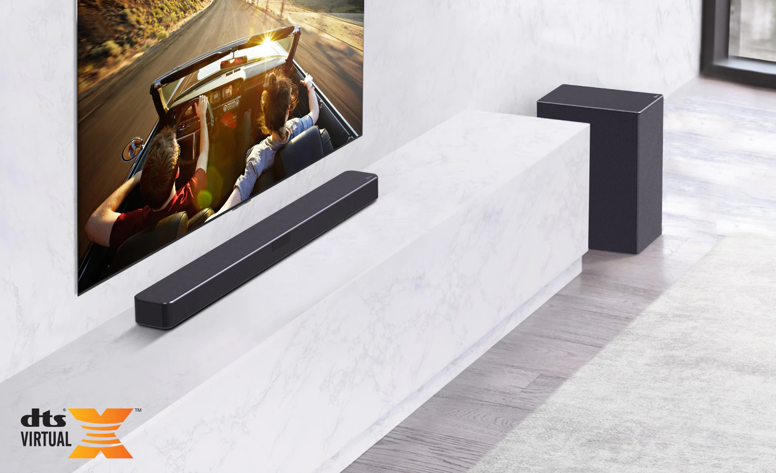 Il televisore è sulla parete, la soundbar LG è in basso su un ripiano in marmo bianco con un subwoofer a destra.